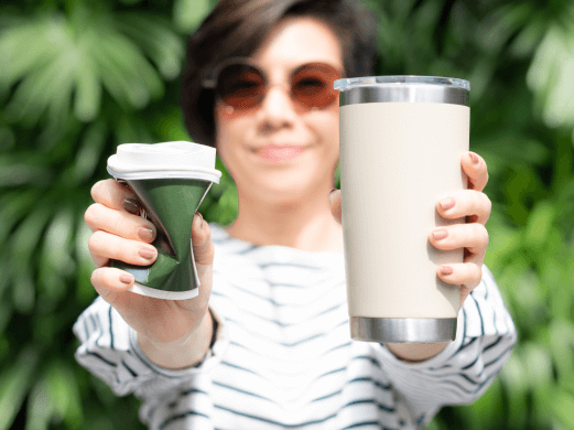 A girl holding a reusable coffee mug in one hand and smashing a plastic cup in another