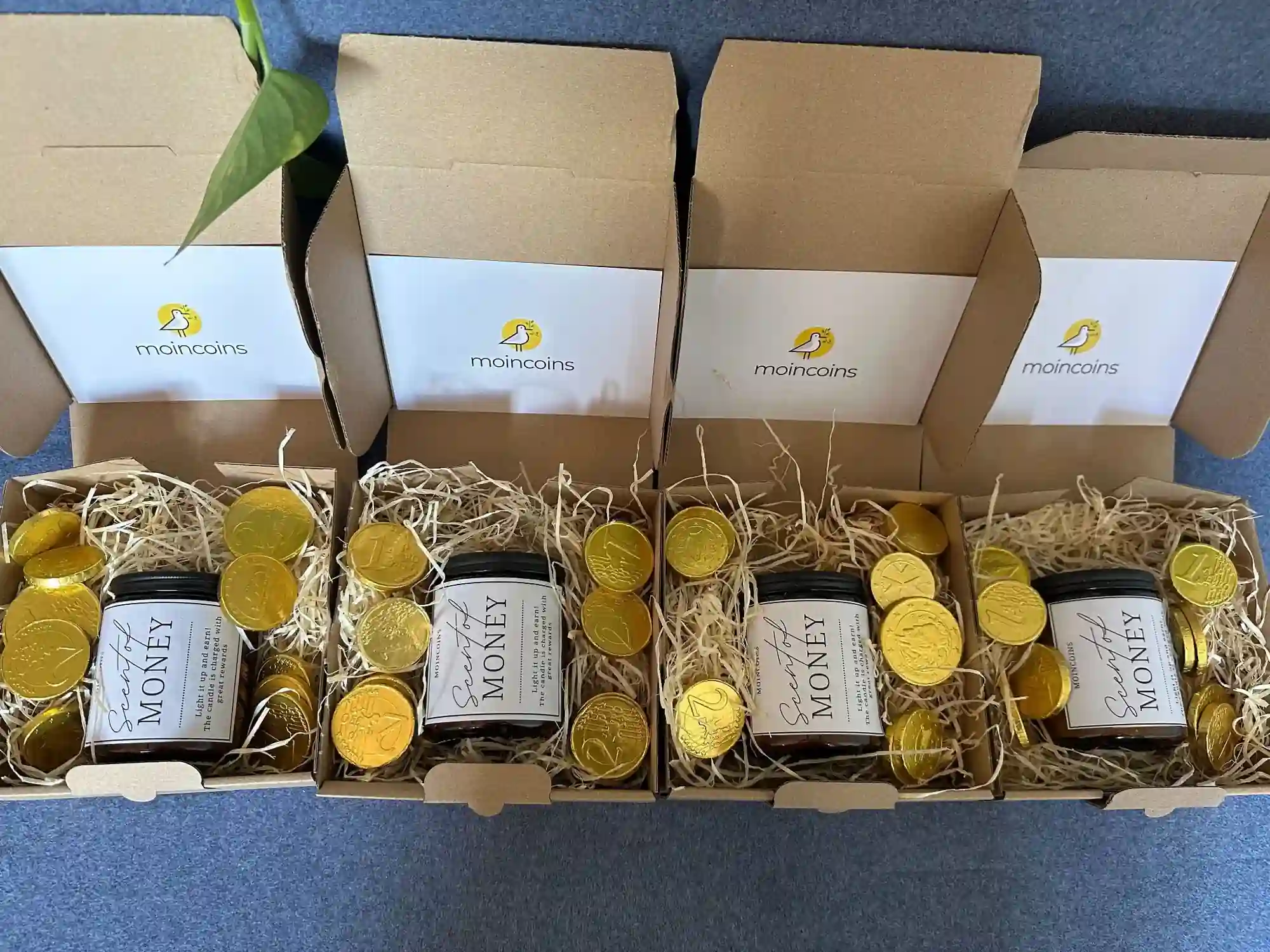 Moincoins 5th anniversary gift boxes with candles, chocolate coins, and thank-you letters arranged together.